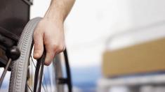 Hand auf dem Rad eines Rollstuhls, Rollstuhl